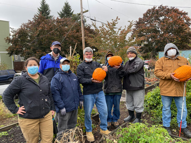 EMSWCD staff Monica (left) standing with several participants at a Voz event, all pausing for a picture. Most are wearing masks and some of the participants are holding up pumpkins