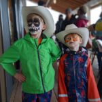 Two young boys wearing cowboy hats with faces painted.