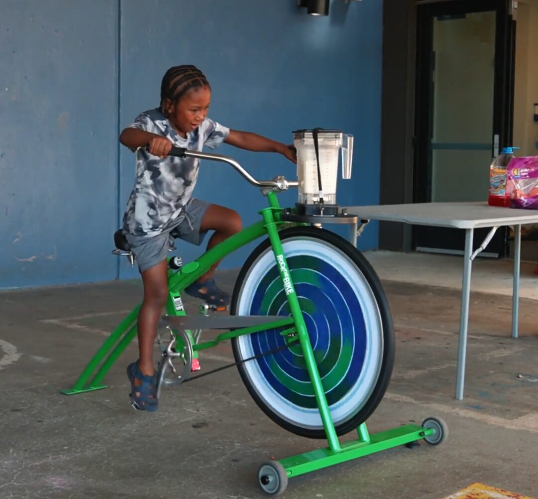 young person pedaling a bike to mix a smoothie